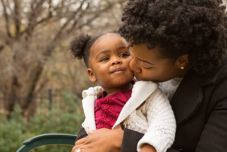 Post-pregnancy care for birth moms, Dark-skinned mom kisses the cheek of her toddler daughter