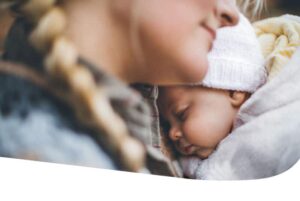 a woman with a braid nestles a sleeping infant