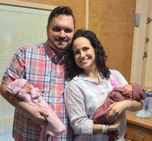 a smiling adoptive couple with newborn twins in a hospital room.