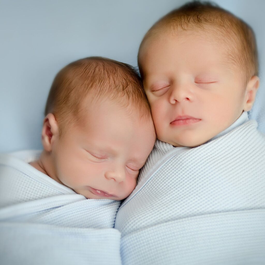 twin newborn boys sleeping wrapped in light blue blankets